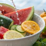 Spalvingas vaisių dubuo su arbūzu, agurkais ir citrusiniais vaisiais, pabrėžiant diuretikų savybes ir hidrataciją.